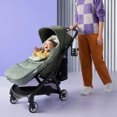 Bugaboo Butterfly ขณะใช้งานจริง — ผู้ปกครองเข็นเด็กเล็กในรถเข็นที่กางออก พร้อมขวดน้ำติดด้ามจับ